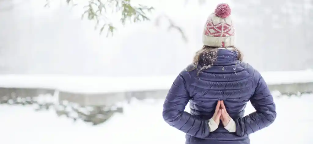 woman standing in the snow with her hands behind her back